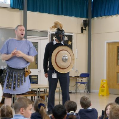 Ancient Greek presenter and our teacher in a helmet with a shield 