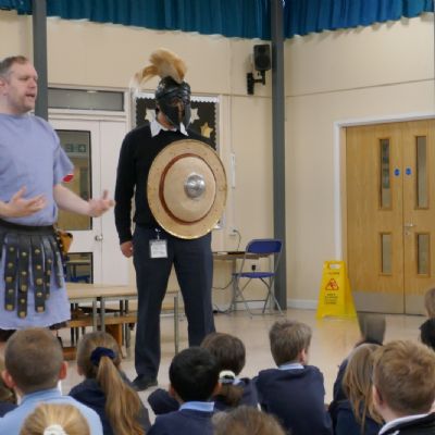 Ancient Greek presenter and our teacher in a helmet with a shield 