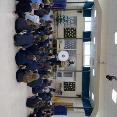 Ancient Greek presenter and our teacher in a helmet with a shield and spear with pupils in the foreground.