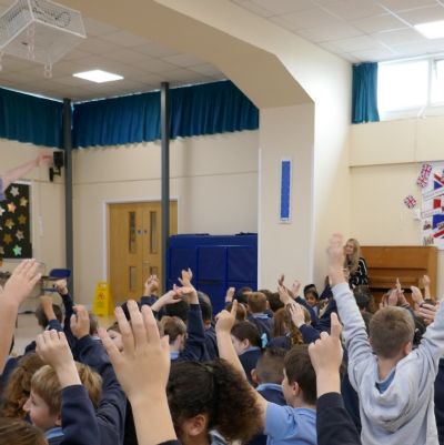 Ancient Greek presenter with the pupils in the foreground waving their arms..